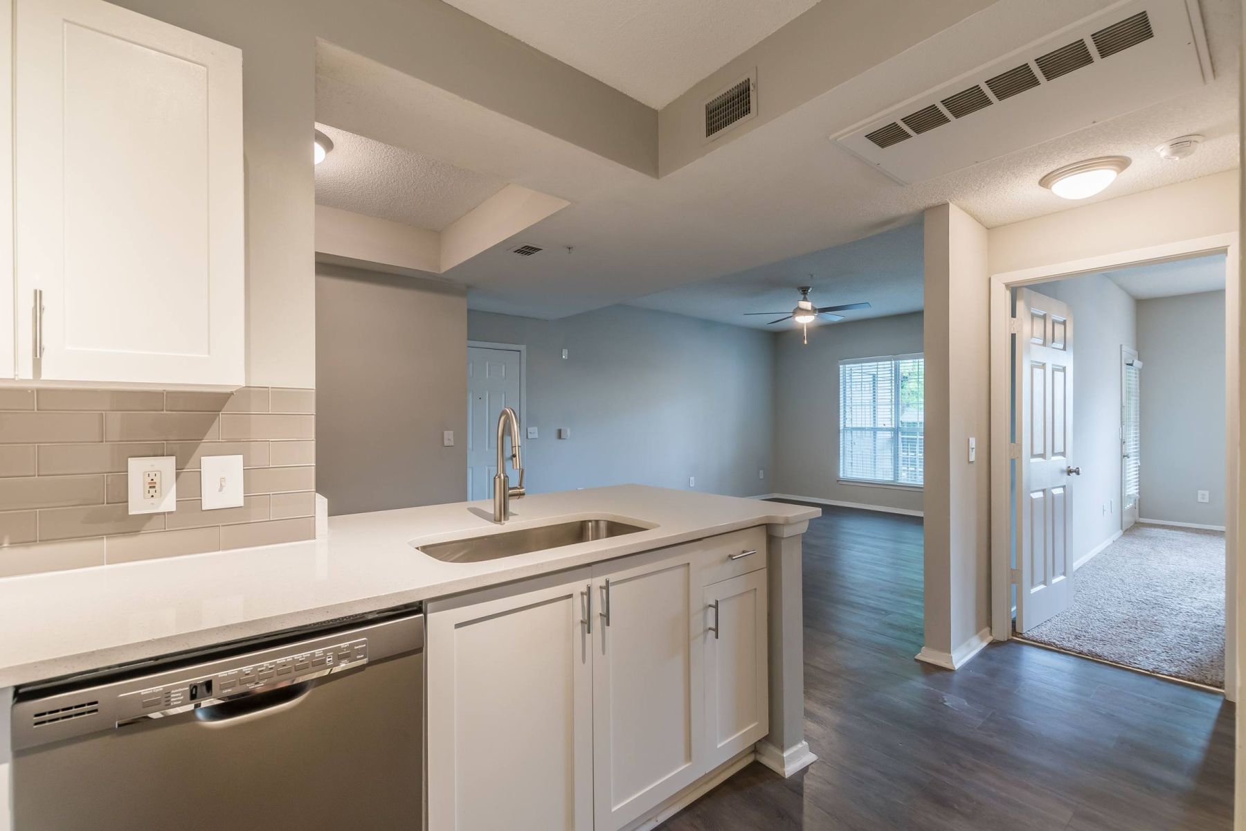 Empty room with wood floors, ceiling fan, and sliding glass door leading to a patio with vertical blinds at Apex West Midown.